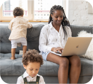 Un parent travaille devant un ordinateur pendant que ses enfants jouent avec lui.